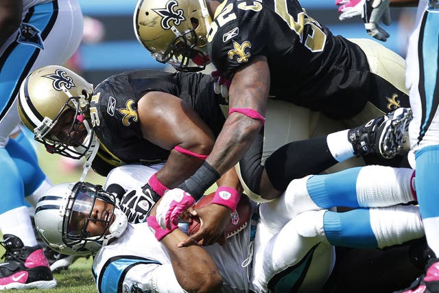 New Orleans Saints players Will Smith and Jonathan Casillas leave Cam Newton of Carolina Panthers down and out during an NFL match
