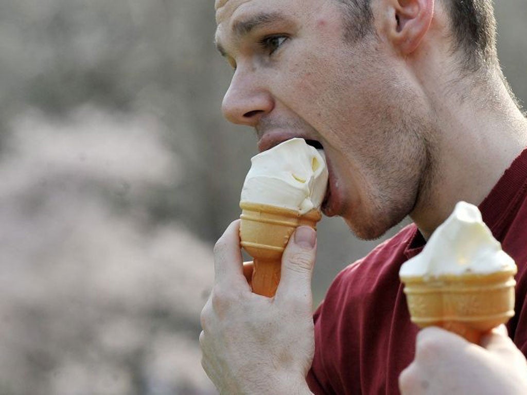 A man enjoys an ice cream during the warm summer-like temperatures in London today