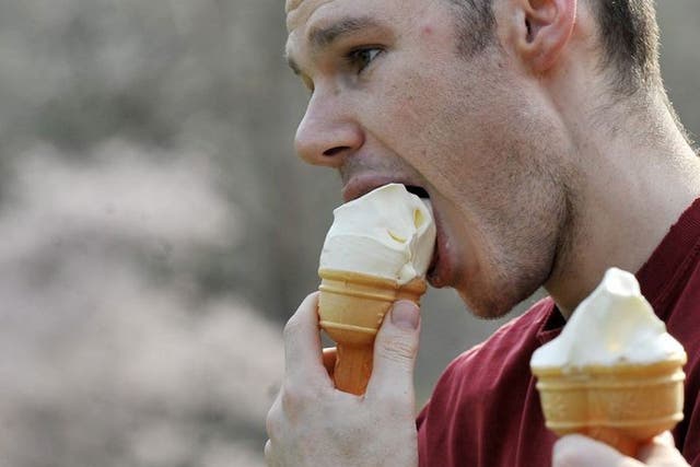 A man enjoys an ice cream during the warm summer-like temperatures in London today