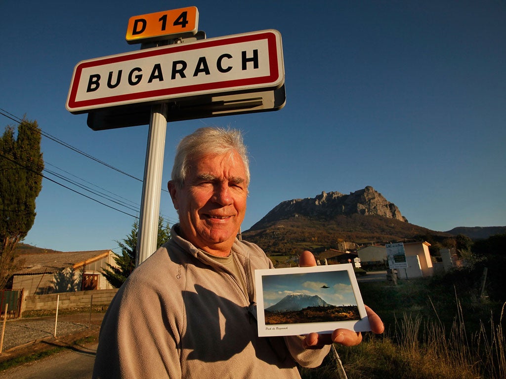 Jean-Pierre Delord, Bugarach's mayor, with a postcard of a UFO hovering over a local peak