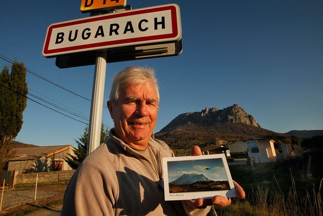 Jean-Pierre Delord, Bugarach's mayor, with a postcard of a UFO hovering over a local peak