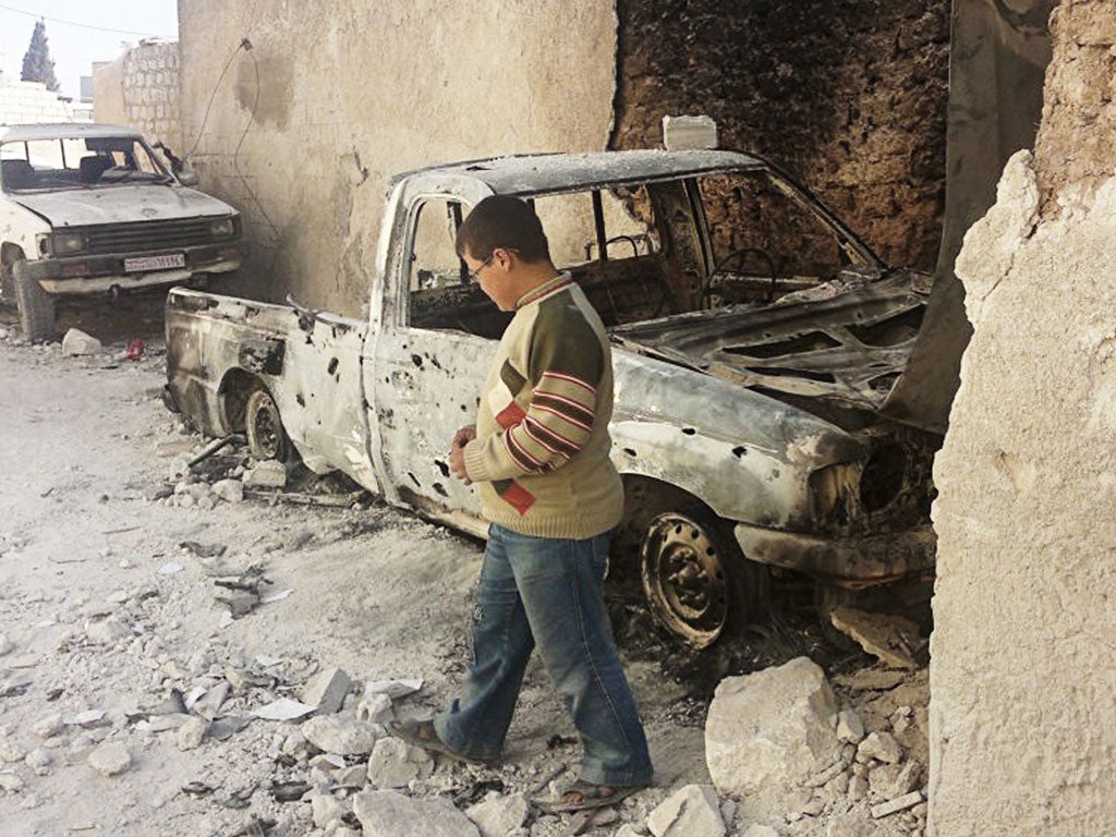 A boy looks at cars hit by Syrian army artillery in the town of Sarmeen