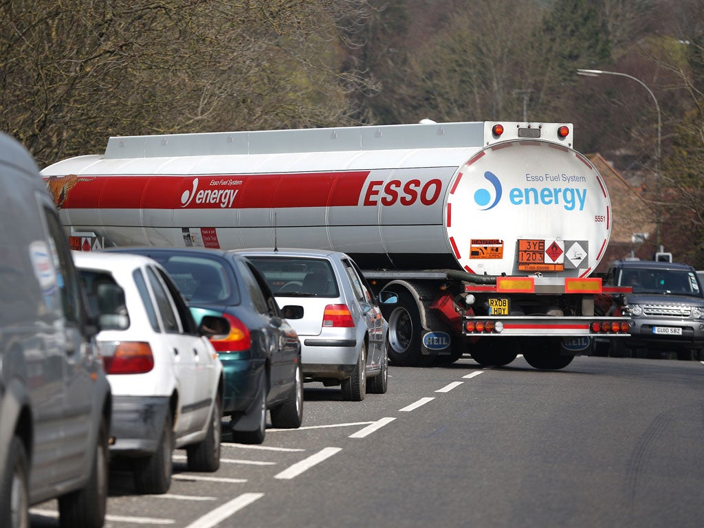 A petrol tanker moves through a line of queuing cars after replenishing supplies at a previously closed garage in Brighton today