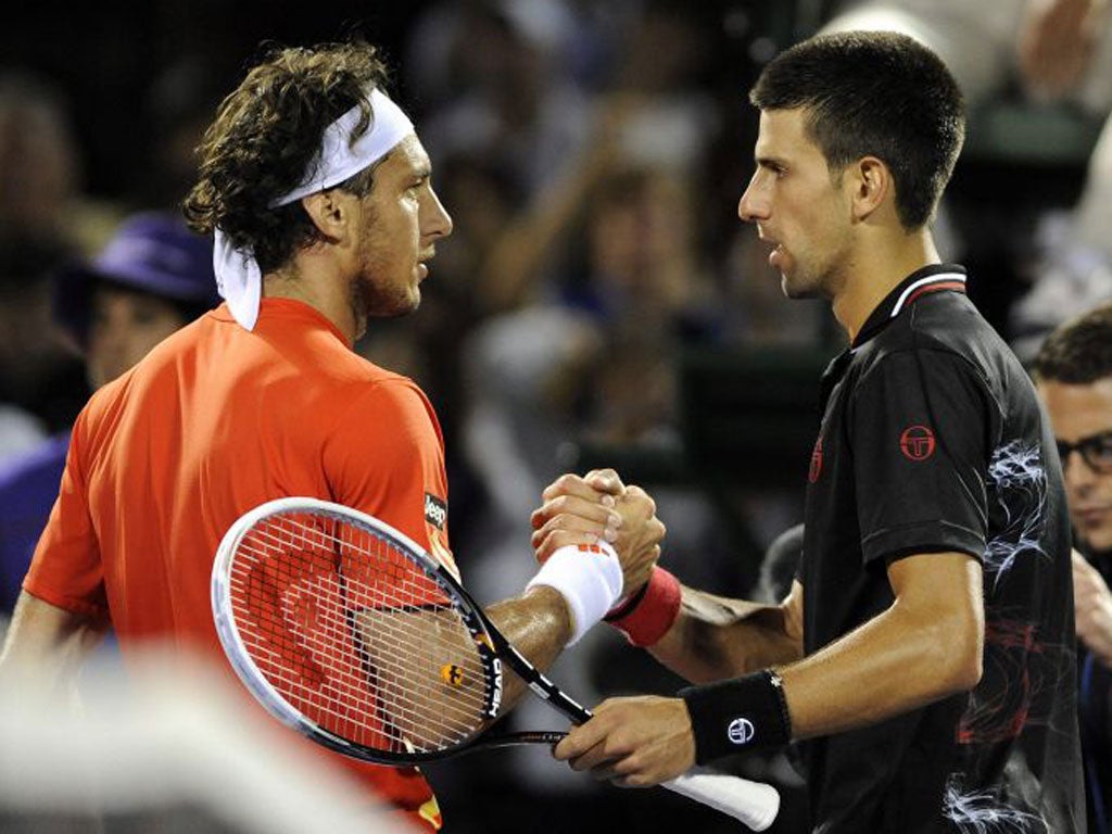 Juan Monaco of Argentina (left) and Novak Djokovic of Serbia meet at the net following their match at the Florida Open.