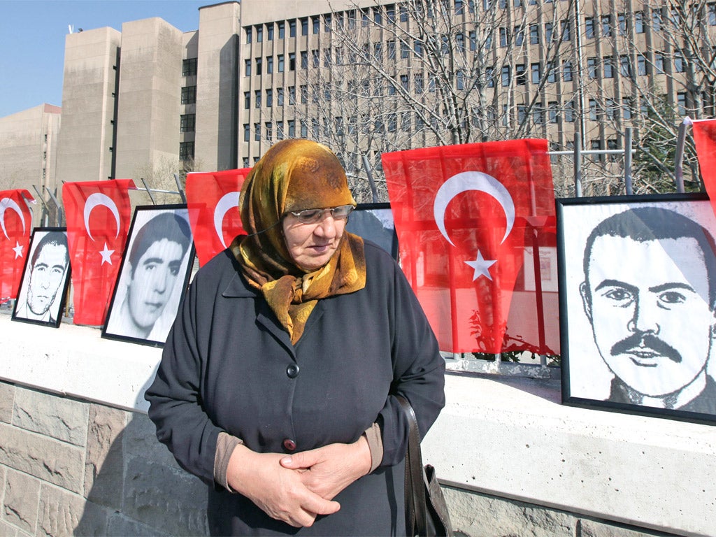 A woman stands in front of portraits of youths who were executed, died or disappeared in jails during military rule after Turkey's 1980 coup