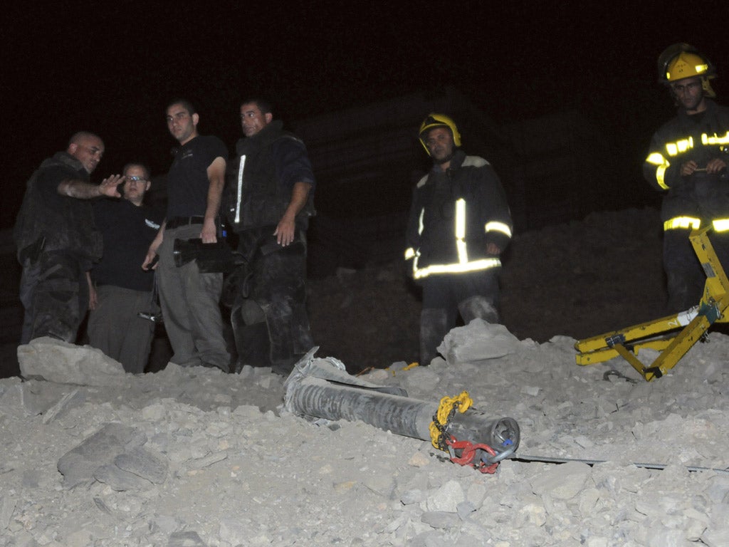 Israeli police stand next to a rocket that landed in the resort town of Eilat