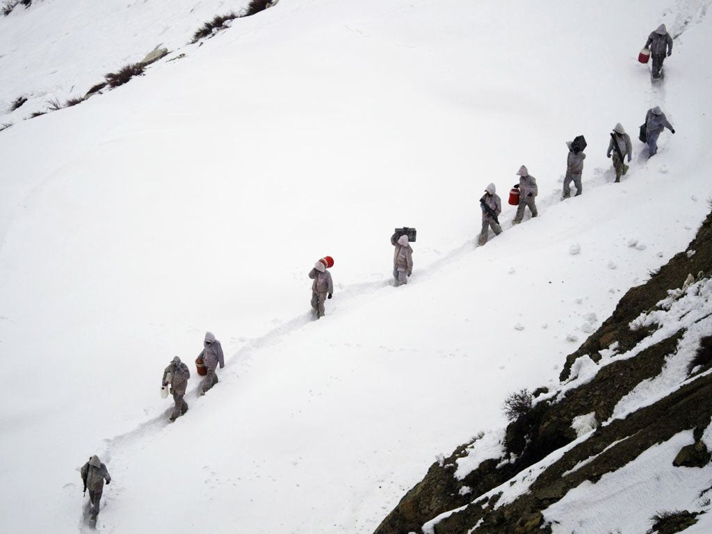 Pakistani soldiers are seen carrying supplies up the 8,000-foot mountain near their outpost, Kalpani Base, which was hit by an avalanche today