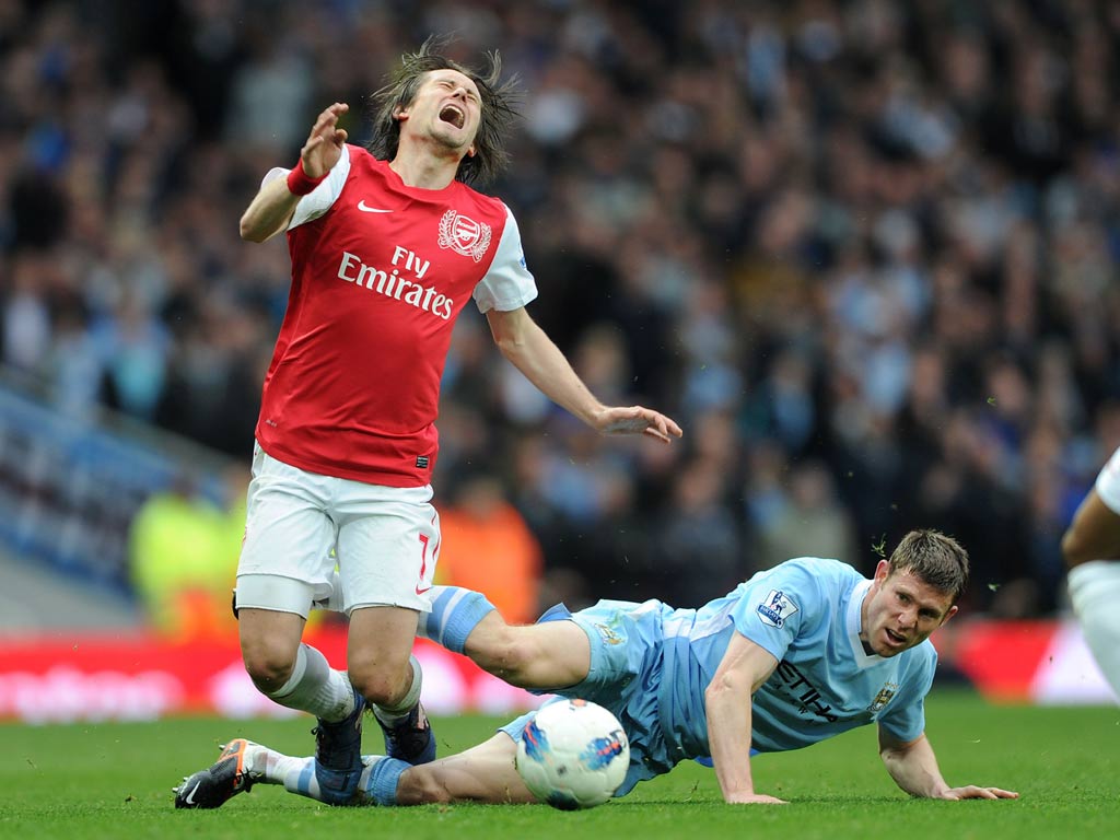 Tomas Rosicky is challenged by James Milner