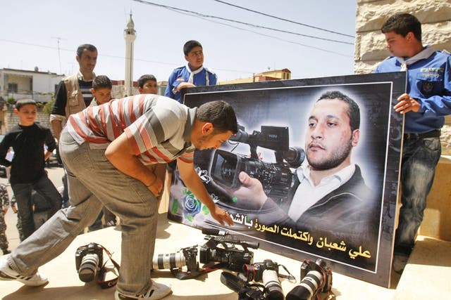 Colleagues laying down cameras in front of a portrait of the Lebanese cameraman Ali Shabaan at his funeral in the village of Maifadoun