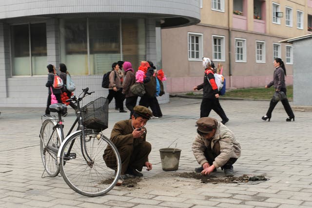 Workers repair a road by hand
