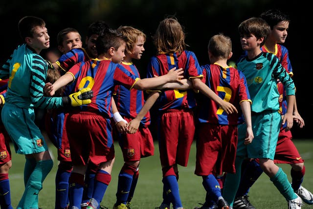 Pure kidology: Barcelona's youngsters form a huddle before kick-off at the club's La Masia training ground; they play in exactly the same way as the senior team