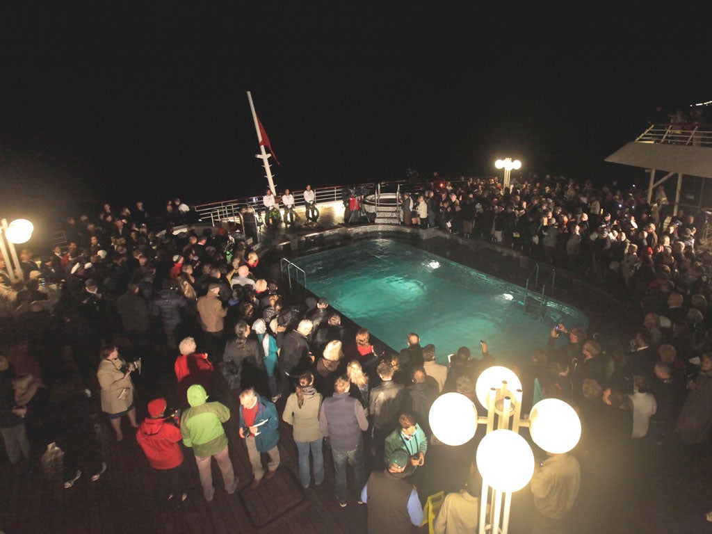 Passengers participate in a memorial service, marking the 100th year anniversary of the Titanic disaster, aboard the MS Balmoral Titanic memorial cruise ship