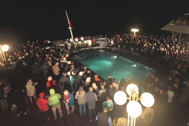 Passengers participate in a memorial service, marking the 100th year anniversary of the Titanic disaster, aboard the MS Balmoral Titanic memorial cruise ship