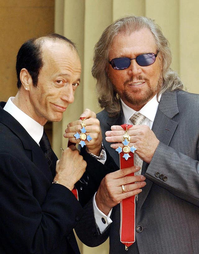 Robin and Barry Gibb hold their CBEs after receiving them from the Prince of Wales at Buckingham Palace, London, 27 May, 2004.