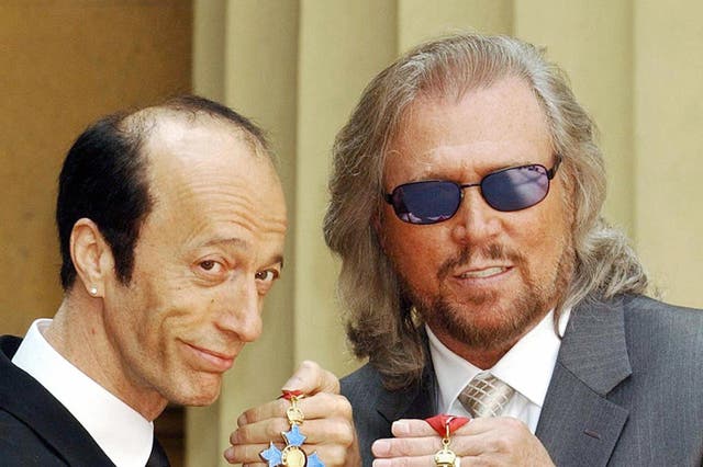 Robin and Barry Gibb hold their CBEs after receiving them from the Prince of Wales at Buckingham Palace, London, 27 May, 2004.