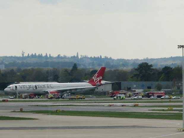 The Virgin Atlantic aircraft stands on the tarmac with emergency service vehicles in support after making an emergency landing at Gatwick Airport