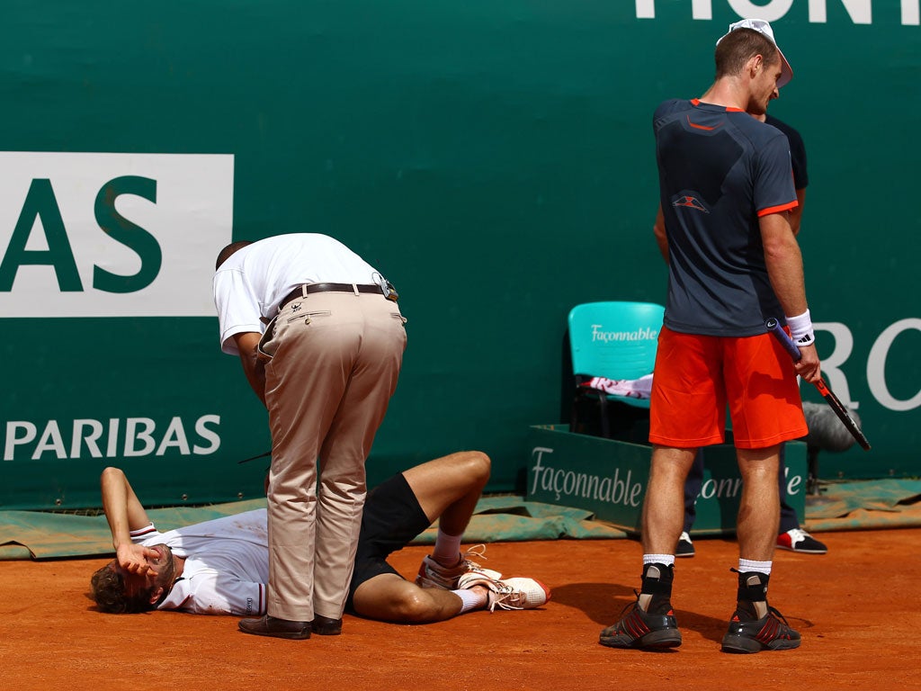 Andy Murray of Great Britain looks away as an injured Julien Benneteau of France receives help