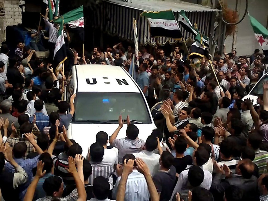A UN observer vehicle is surrounded by a crowd in a suburb of Damascus protesting against the Assad regime