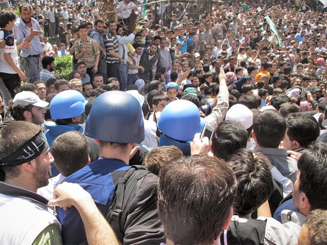 Protesters gather round UN observers during a visit to Douma, a suburb of Damascus, on Monday