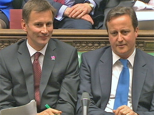 Jeremy Hunt gives a wry smile as he sits next to David Cameron in the Commons