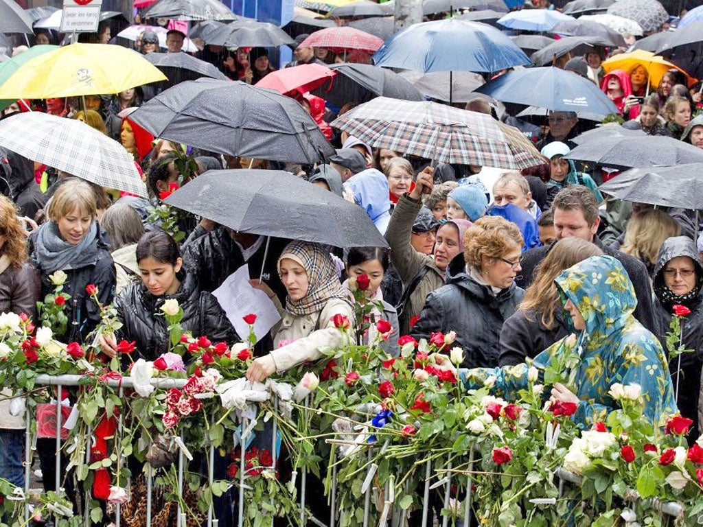 People gather beside flower decked railings as they sing a song hated by mass murderer Anders Breivik in Oslo yesterday