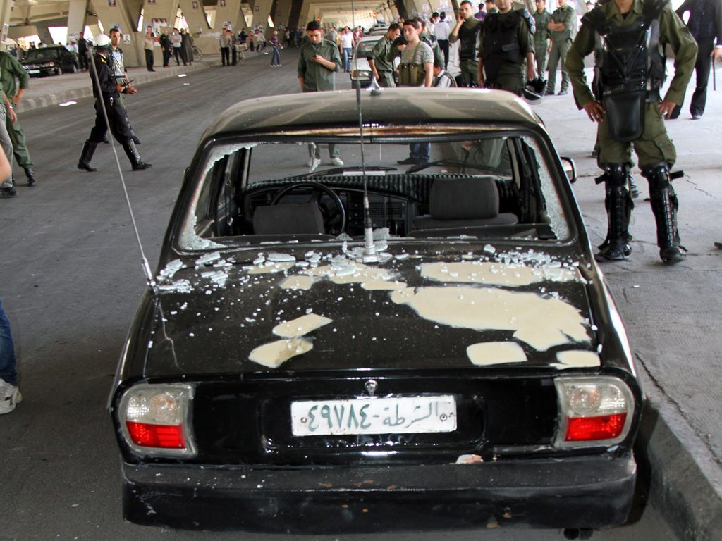 Police stand by a car damaged in one of several bomb attacks in
Damascus yesterday