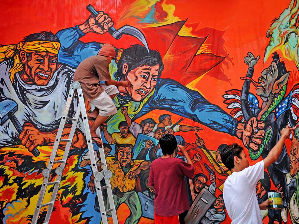 Filipino activists apply the finishing touches on a mural that will be used at the Labor Day at their headquarters in Quezon City