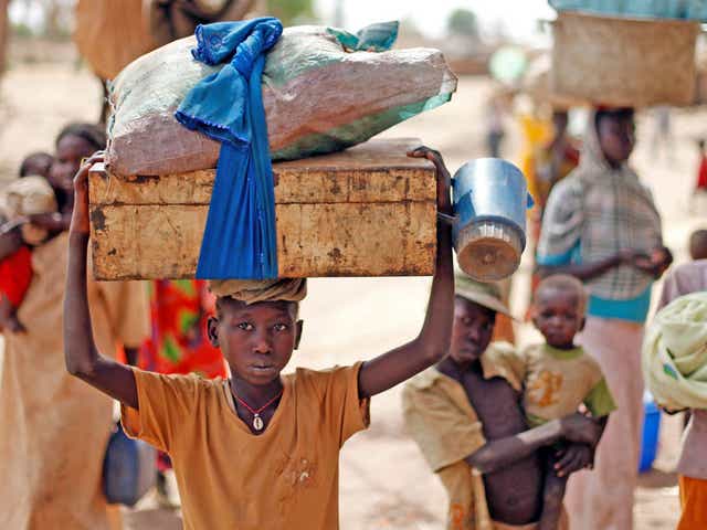 Nuba people carry their belongings to be loaded in a truck as they flee to the South Sudanese Yida refugee camp