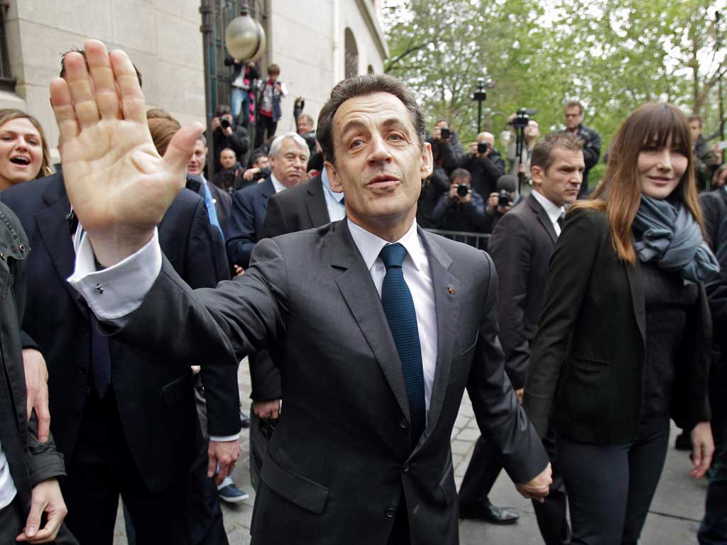 Nicolas Sarkozy and Carla Bruni waving as they leave after voting in the second round yesterday