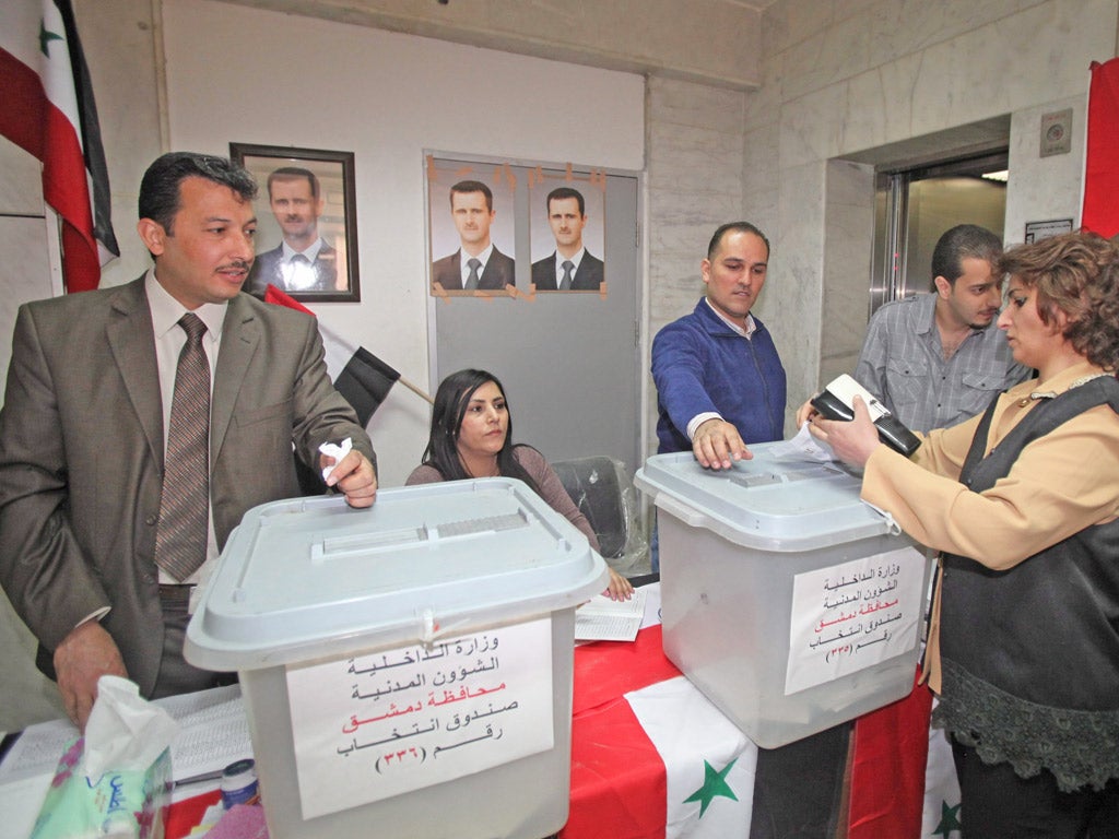 Syrian voters cast their ballots at a polling station in the capital, Damascus, which was festooned with pictures of President Bashar al-Assad