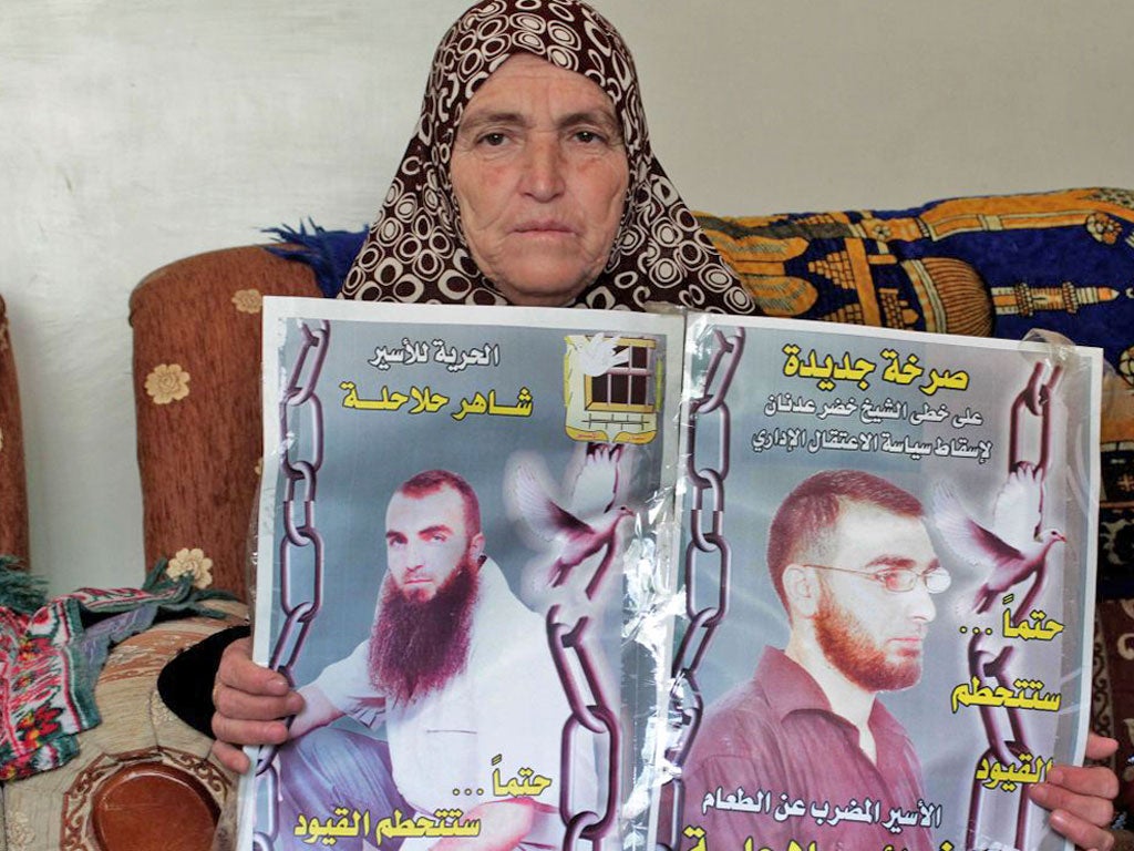 Fatima Halahleh holds posters of her sons Tha’er Halahleh,
right, and Shaher Shaher, who are both on hunger strike in
Israeli jails