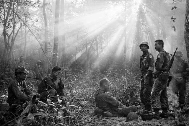 In this January 1965 file photo taken by Associated Press photographer Horst Faas, the sun breaks through dense jungle foliage around the embattled town of Binh Gia, 40 miles east of Saigon, as South Vietnamese troops, joined by US advisers, rest after a cold, damp and tense night of waiting in an ambush position for a Viet Cong attack that didn't come.