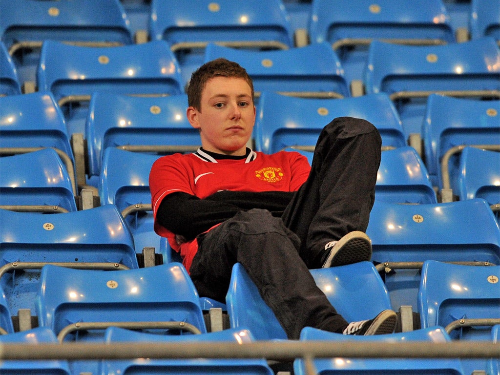 A dejected Manchester United fan cuts a lonely figure following his side's defeat at the Etihad
