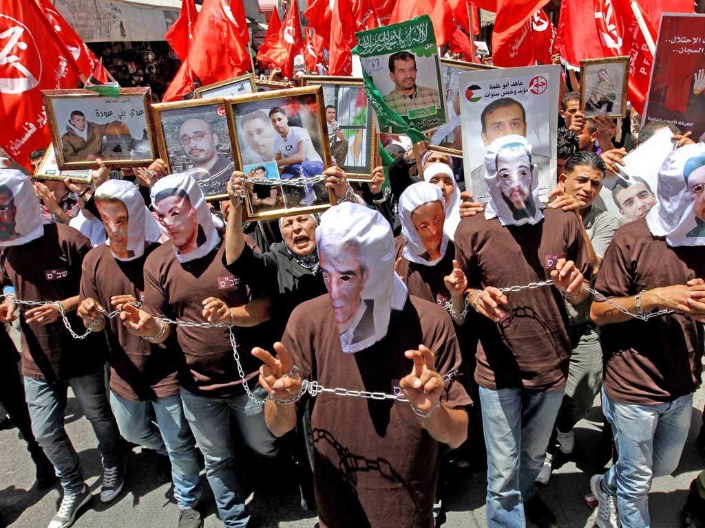 Palestinian protesters wear masks with pictures of the hunger strikers