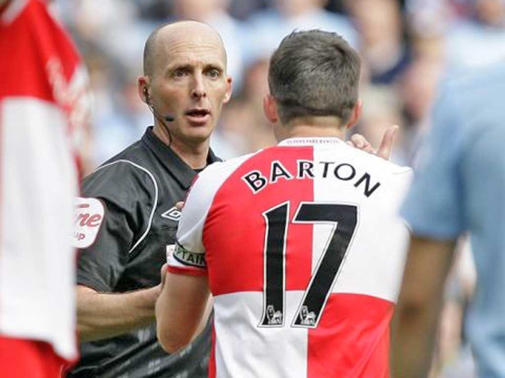 Referee Mike Dean talks to Queens Park Rangers' Joey Barton before giving him a red card during their English Premier League against Manchester City