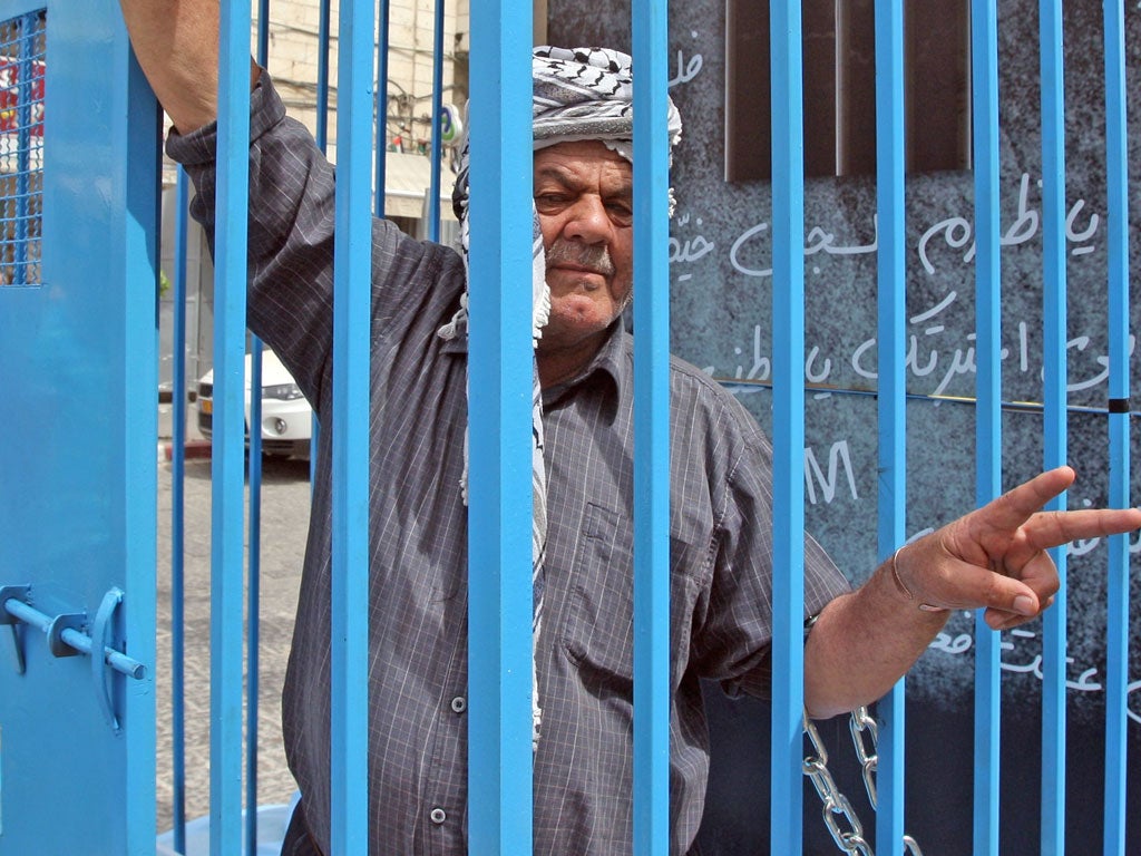 A Palestinian man stands chained to a cage and flashing the sign for victory during a demonstration in the city of Ramallah, in the Israeli occupied