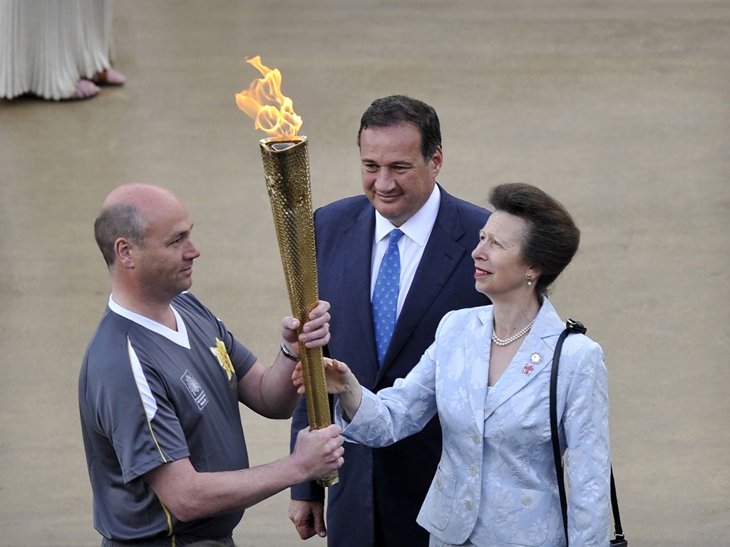 Princess Anne of Britain hands over the torch with the olympic flame to be prepared for the journey to London