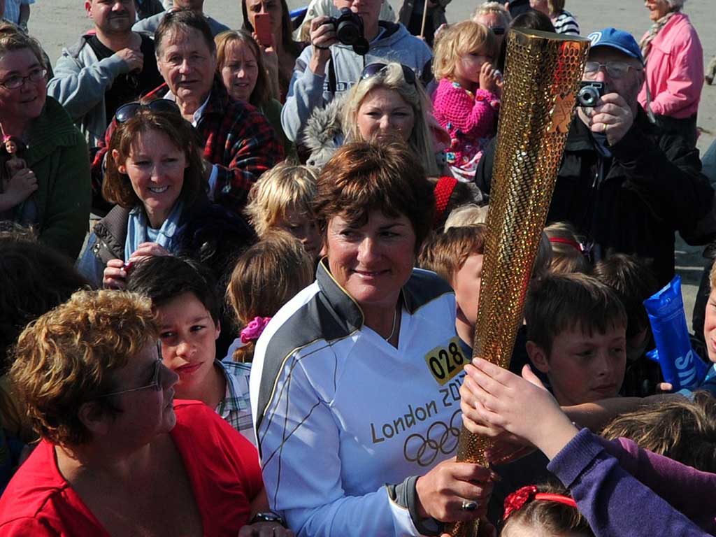Members of the public crowd around Olympic Torch bearer, Sarah Blight, as she holds the torch on the beach near St Michael's Mount in Cornwall