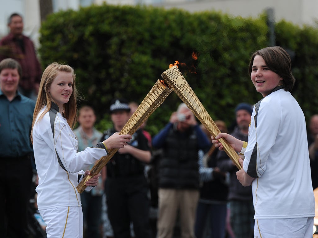 Two torch bearers pass-over the flame as they pass through Newquay, Cornwall