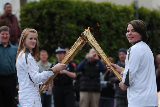 Two torch bearers pass-over the flame as they pass through Newquay, Cornwall
