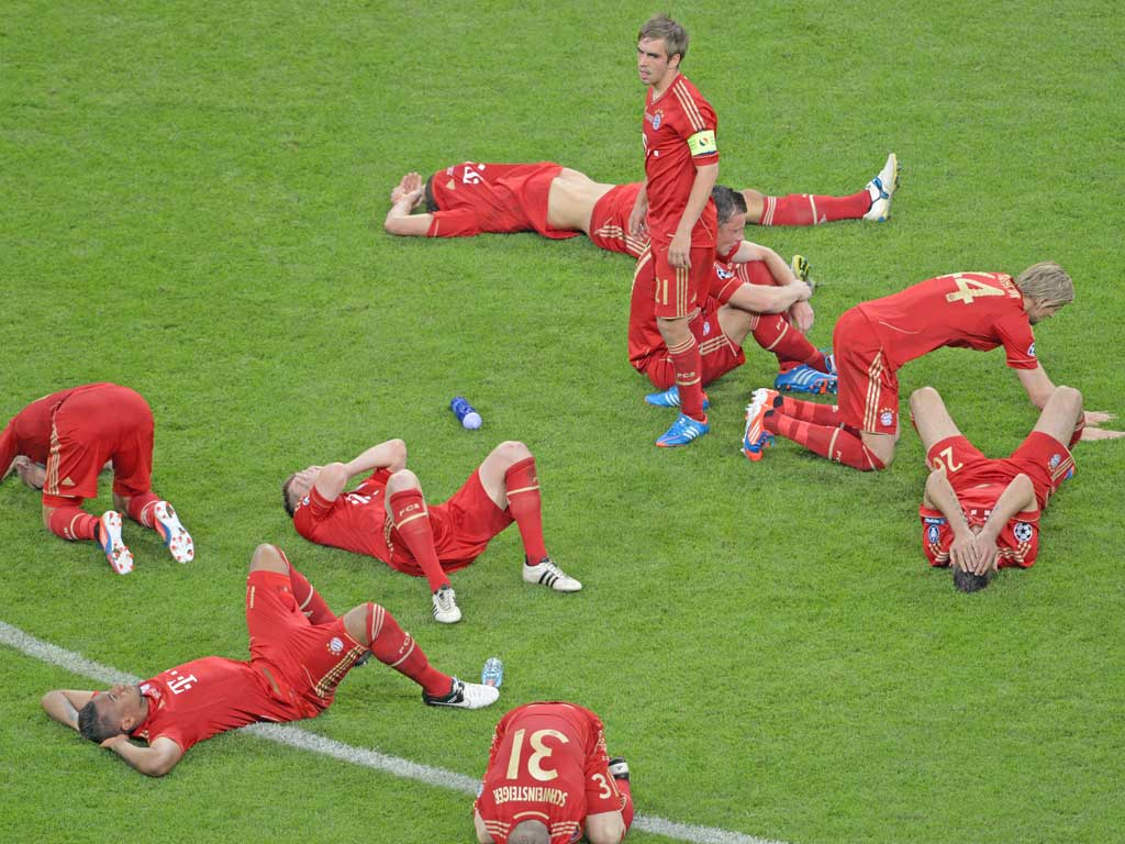 Distraught Bayern Munich players are slumped around captain Philipp Lahm after their defeat
