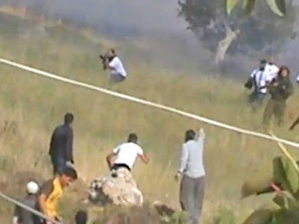 The video shows an armed settler crouching and aiming towards a protester