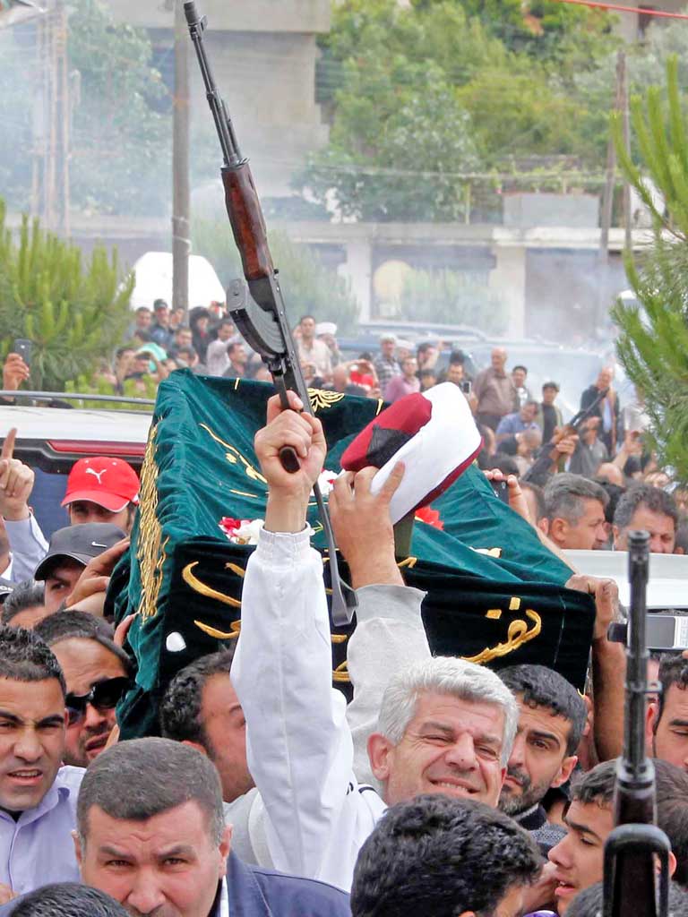 A mourner fires his rifle as the coffin and turban of Sunni cleric Sheikh Ahmed Abdul-Wahid is carried through his home town