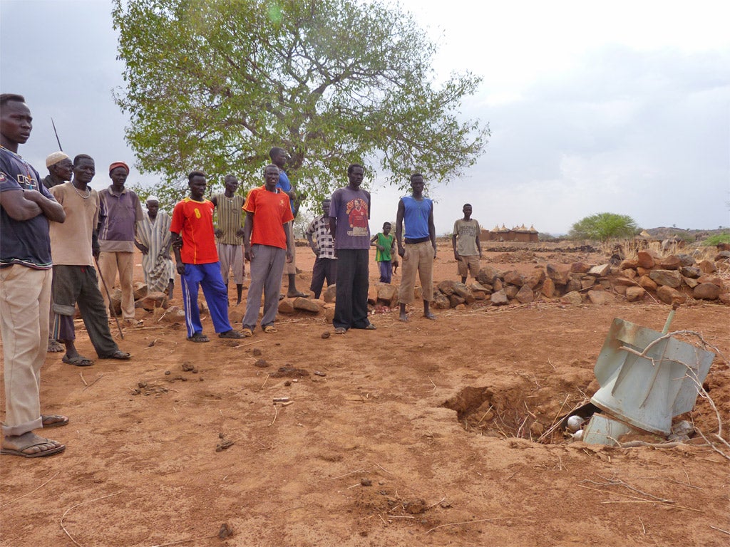 The villagers in Angolo look at the unexploded bomb