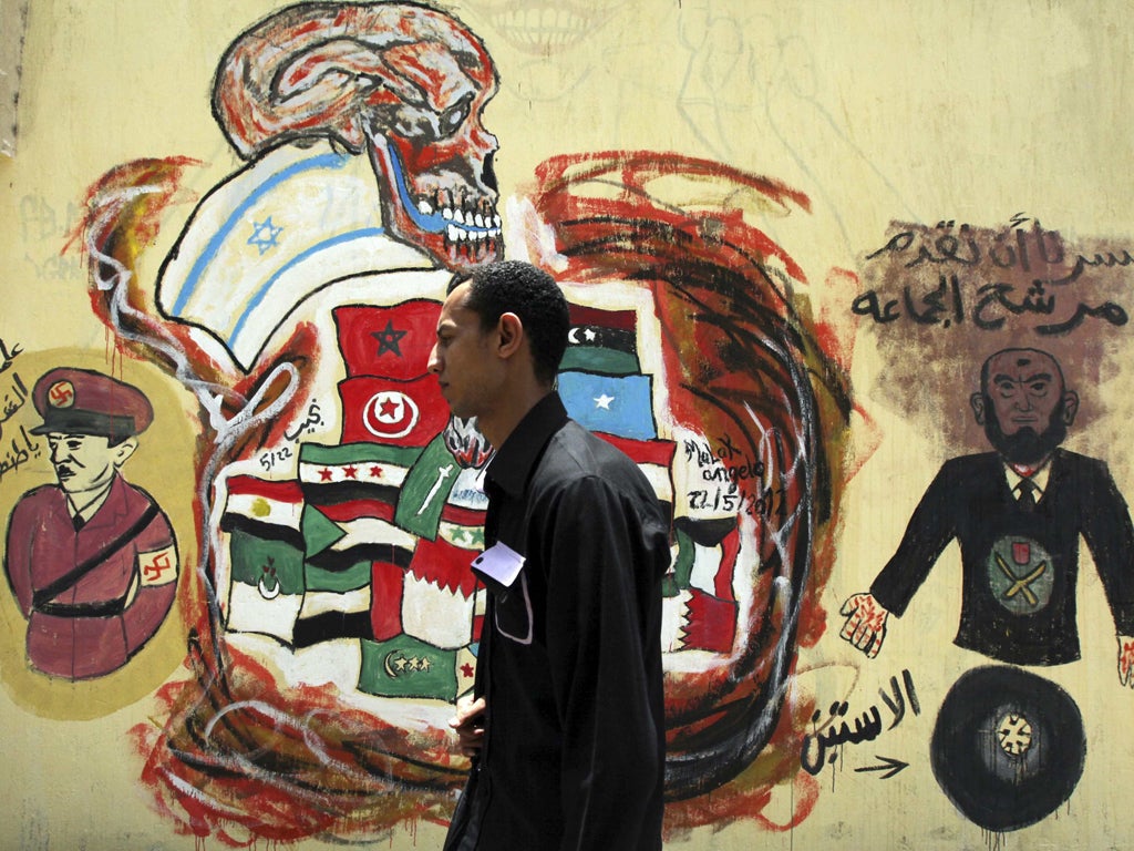 A voter walks past a wall sprayed
with graffiti depicting Egypt's
ruling Military Council and the
Muslim Brotherhood