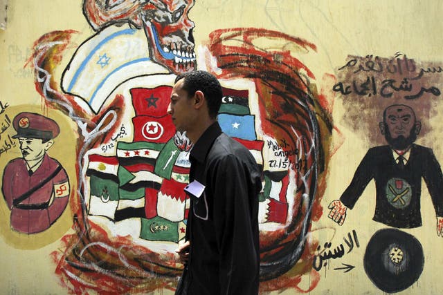 A voter walks past a wall sprayed
with graffiti depicting Egypt's
ruling Military Council and the
Muslim Brotherhood