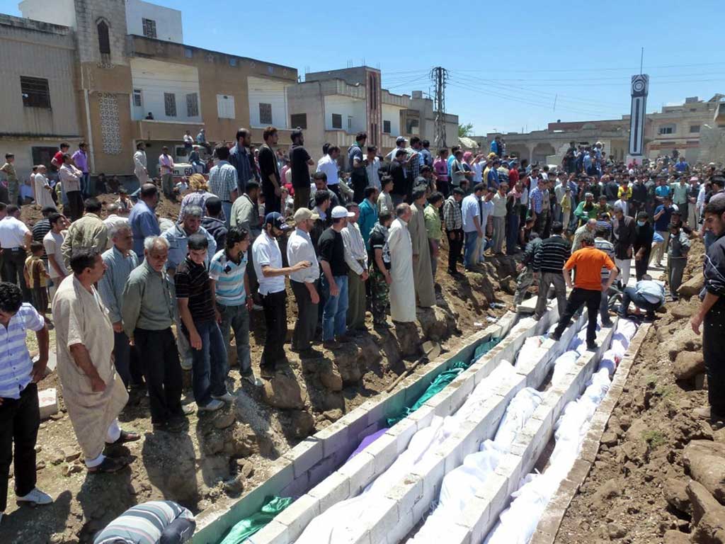 People gather at a mass burial for the victims killed during an artillery barrage from Syrian forces in Houla