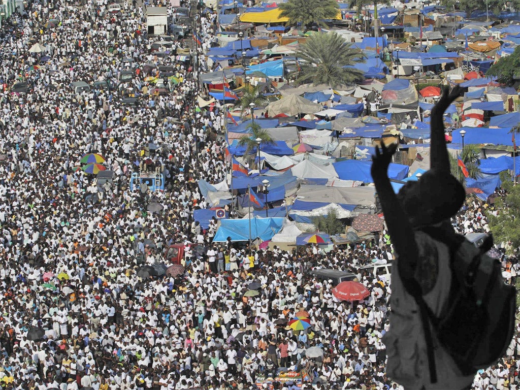 A man holds up his arms in prayer in Port-au-Prince as a crowd marks the earthquake of 2010