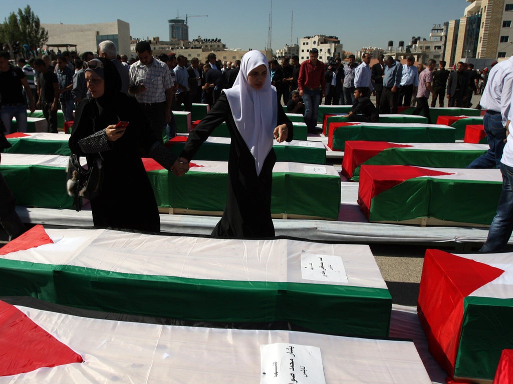 A Palestinian woman looks for a relative among the returned coffins