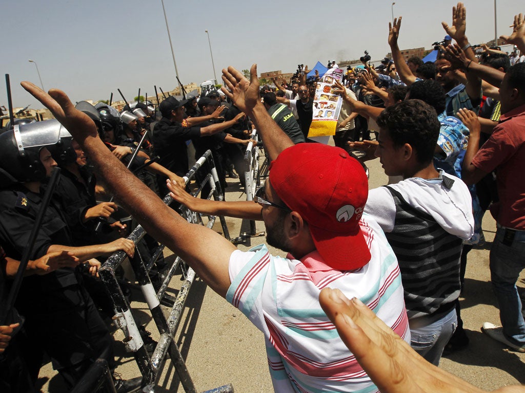 Egyptian riot policemen stand guard as protesters shout slogans against ousted leader Hosni Mubarak outside a Cairo court where his verdict hearing was taking place
